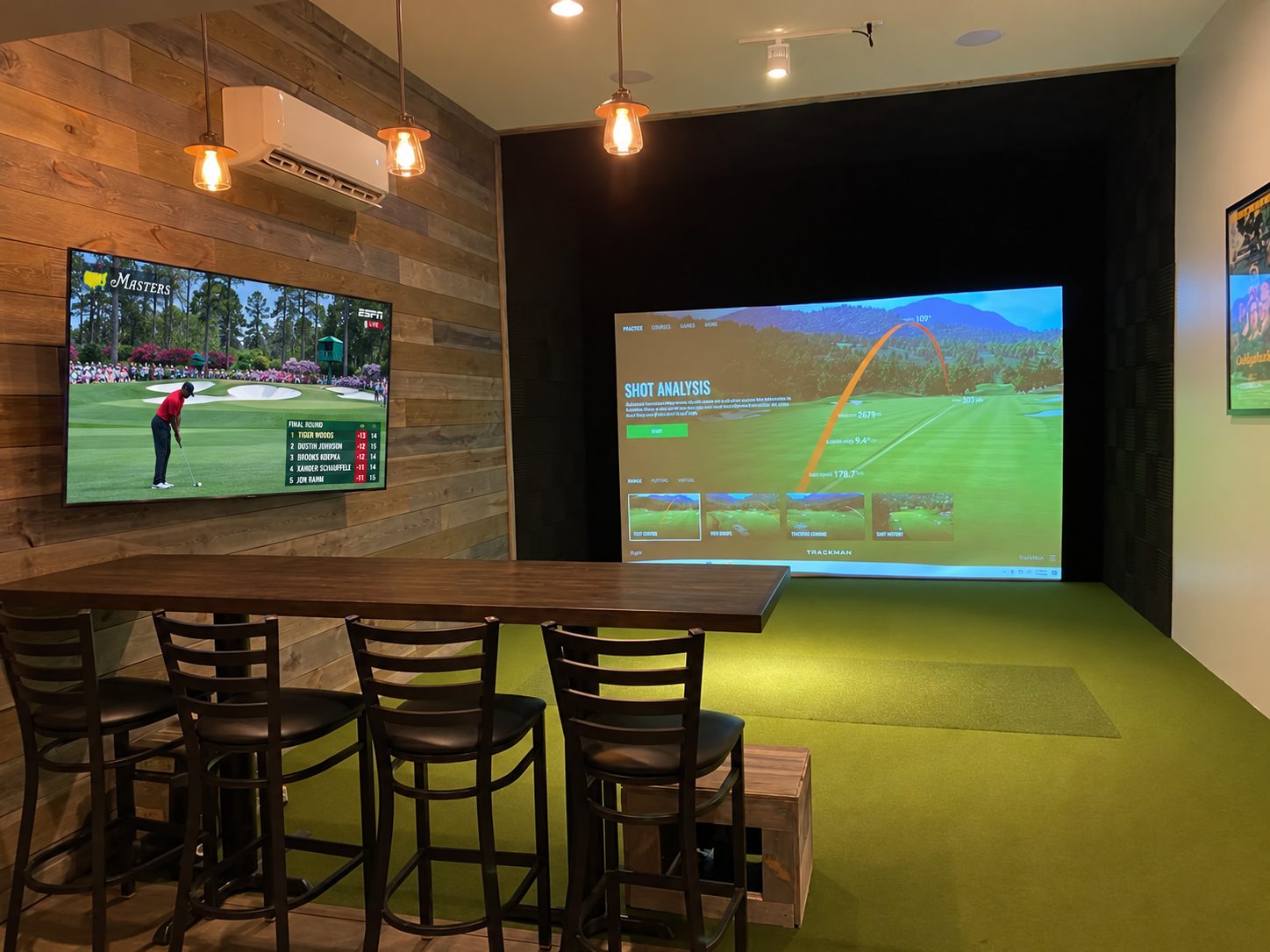 Golf simulator lounge with bar seating and a wall-mounted TV
